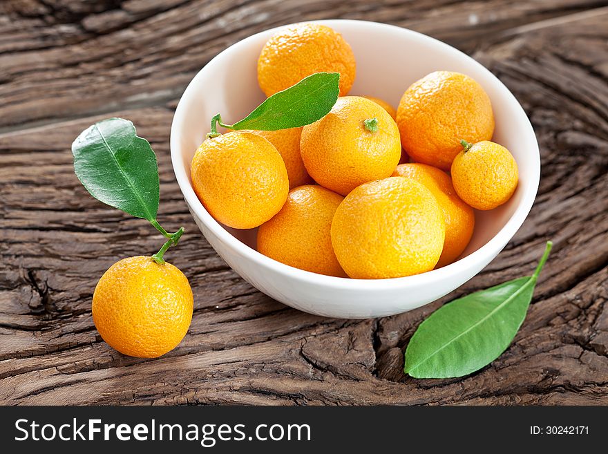 Tangerines in a bowl on old wooden table. Tangerines in a bowl on old wooden table.