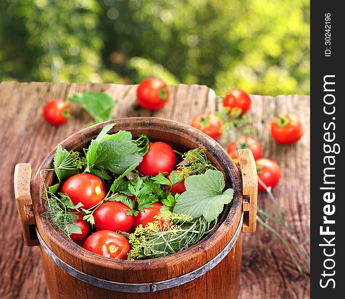 Barrel of pickled tomatoes on an old wooden table.