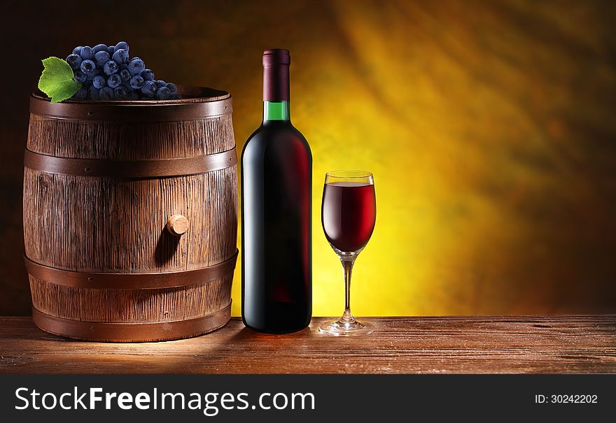 Bottle and a glass of wine with a wooden barrel on dark yellow background with a gradient.