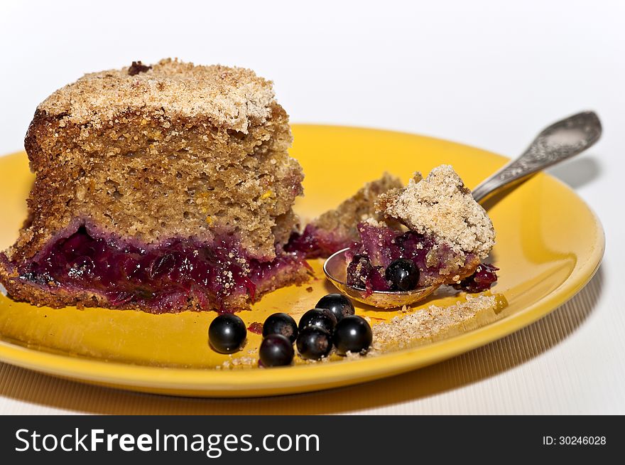 Berry cake on the yellow plate with teaspoon and some black-current