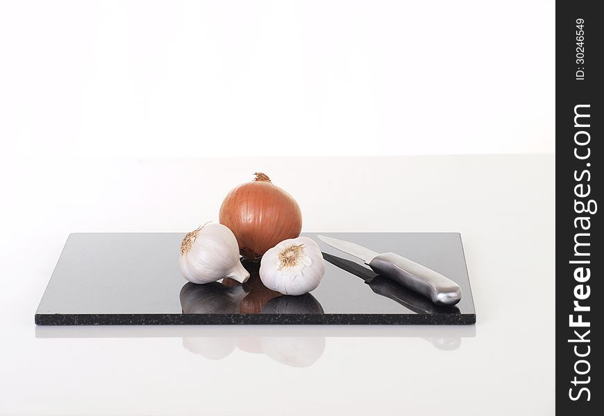 Onions and Garlic on chopping board with knife. Onions and Garlic on chopping board with knife.