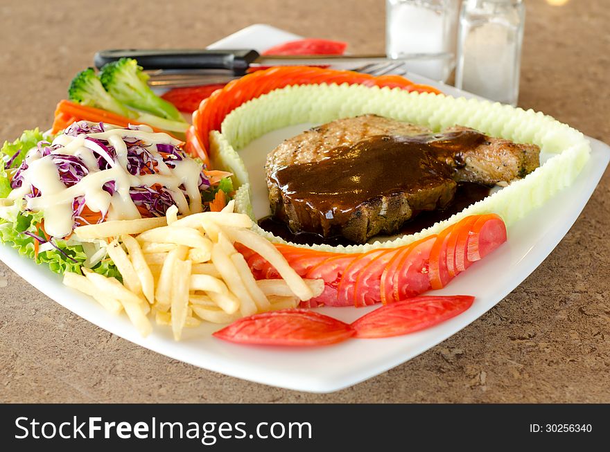 Pork Chop Steak with vegetable salad on white plate