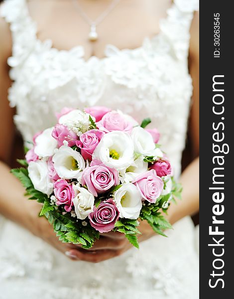 Beautiful wedding bouquet of pink roses in the hands of the bride. Beautiful wedding bouquet of pink roses in the hands of the bride