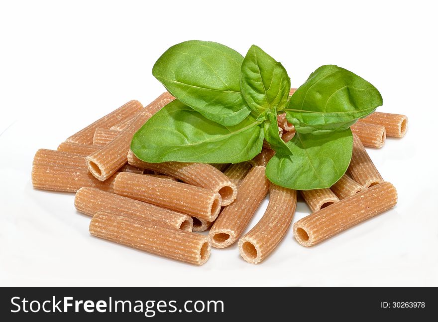 Basil leaves resting on whole wheat rigatoni pasta. Basil leaves resting on whole wheat rigatoni pasta.