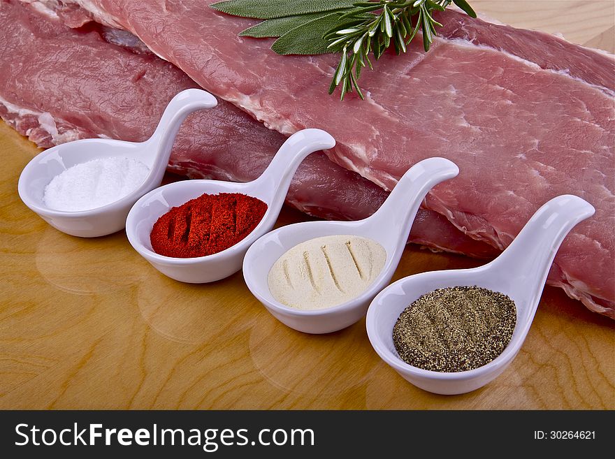 Two pieces of raw pork ribs and spices on a wooden table. Two pieces of raw pork ribs and spices on a wooden table