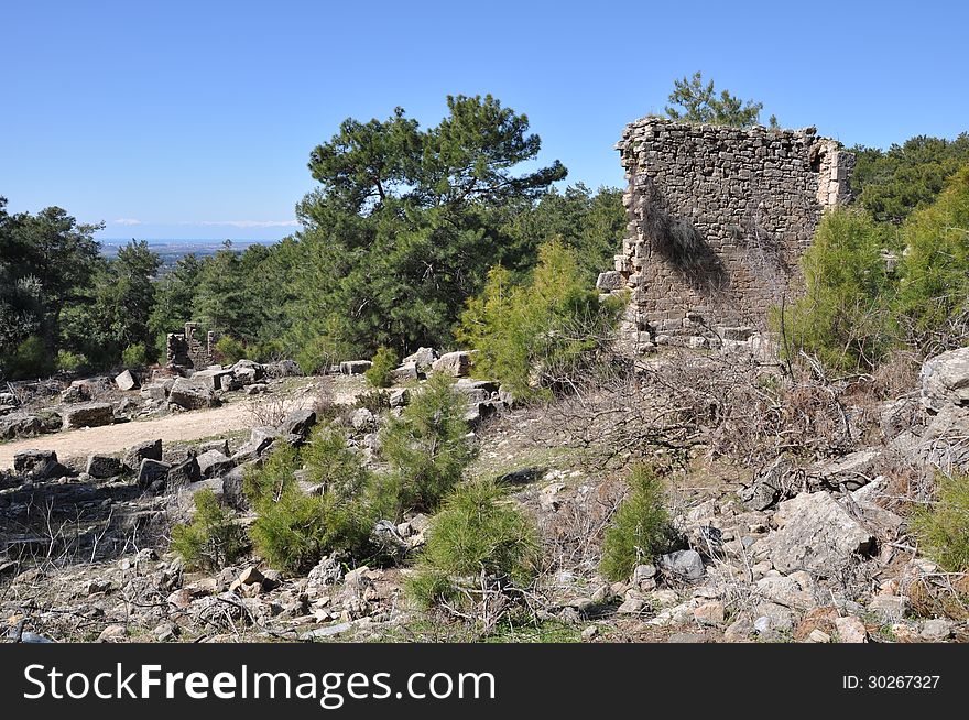Image shows details of Antique Selce, Turkey. Image is dominated by ruins in the front and in the middle. Sky is blue and light cloudy.