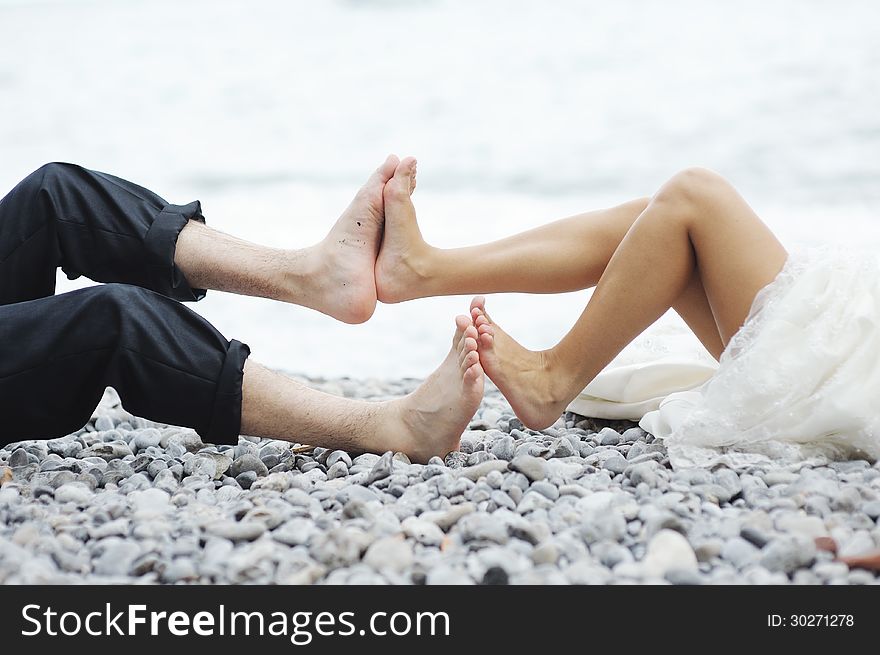 Funny scene between bride and groom feet by the sea. Funny scene between bride and groom feet by the sea