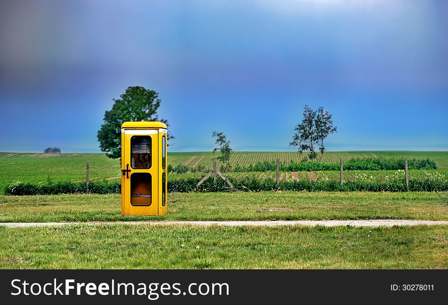 Antiquated yellow phone box is standing lonely in the nature. Antiquated yellow phone box is standing lonely in the nature