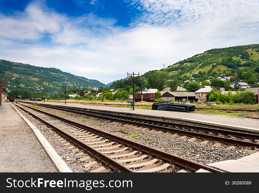 Railroad of railway station in countryside which goes through the mountains under blue sky. Railroad of railway station in countryside which goes through the mountains under blue sky