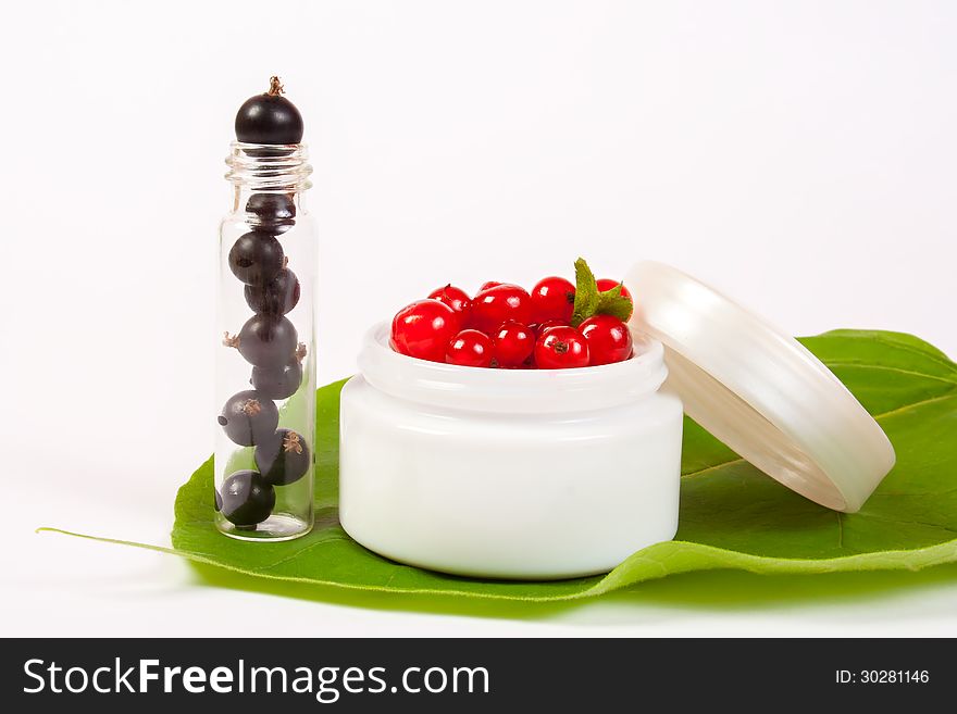 Concept natural cosmetics made of redcurrant and black currant put on white background with green leafs. Concept natural cosmetics made of redcurrant and black currant put on white background with green leafs