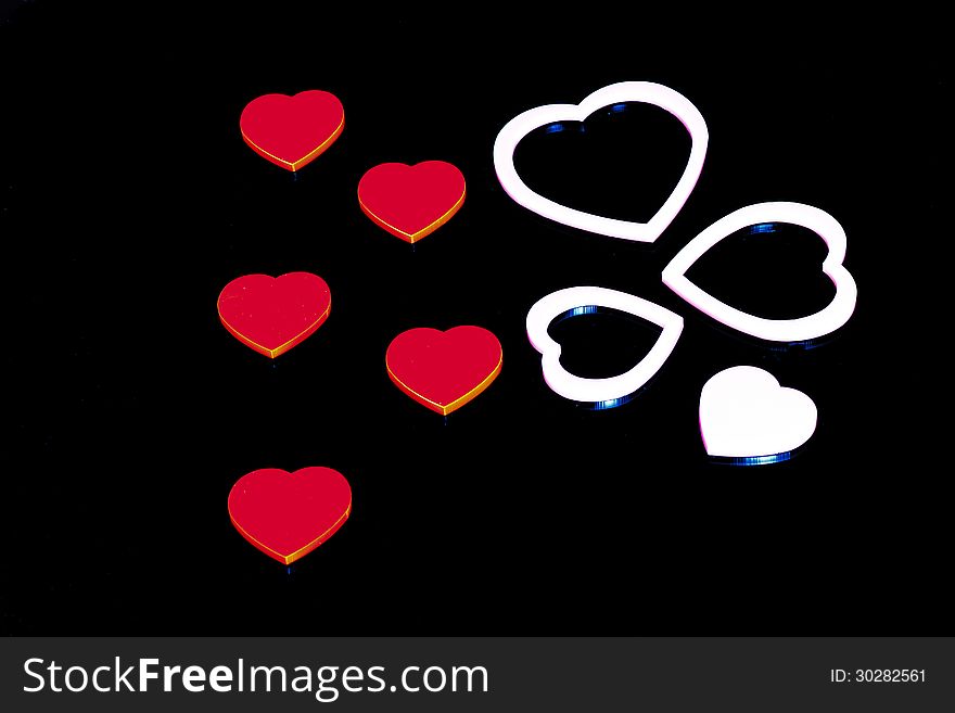 Plastic coloured hearts in a black background