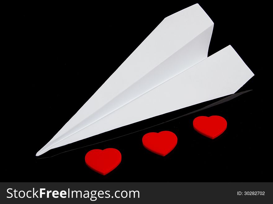 Paper plane and three plastic red hearts