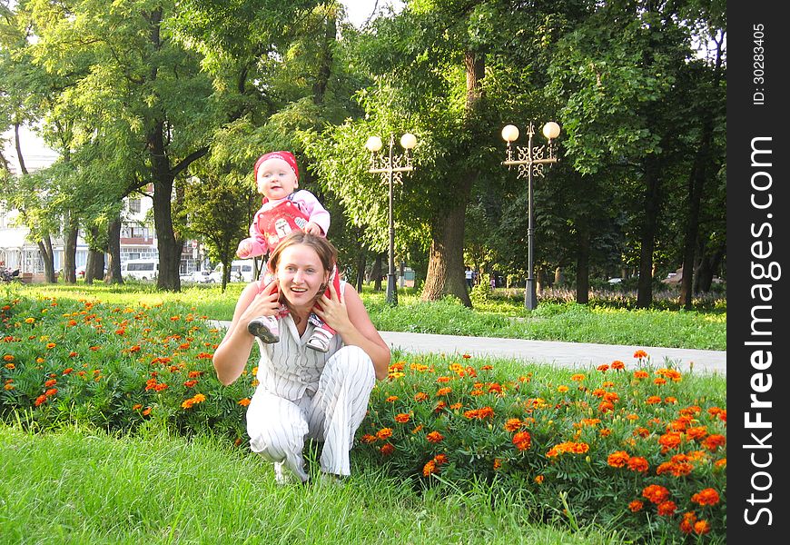 Happy mother and the daughter having a rest in park with flowers. Happy mother and the daughter having a rest in park with flowers