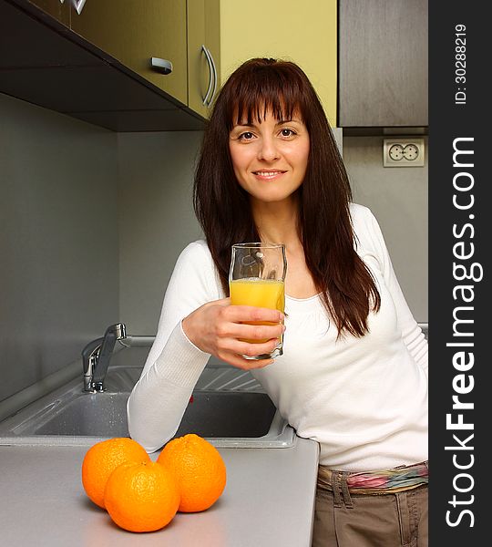 Beautiful woman drinking orange juice in kitchen