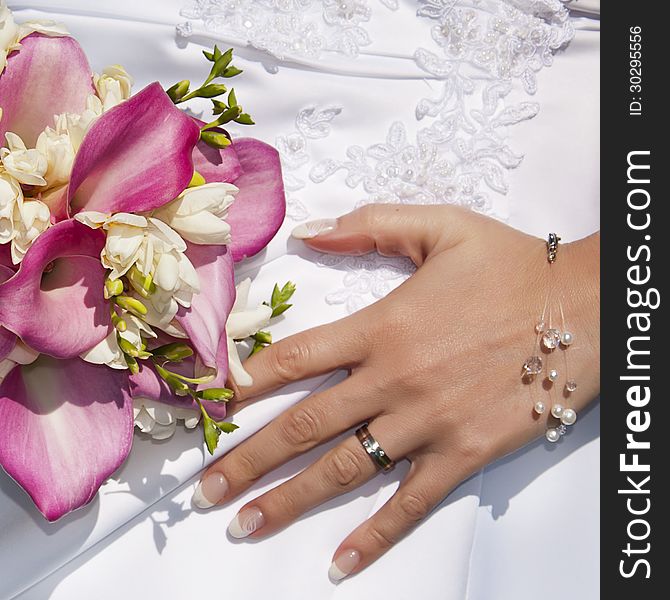 Wedding ring on hand of a bride with lilie bouquet and white bridal dress. Wedding ring on hand of a bride with lilie bouquet and white bridal dress.