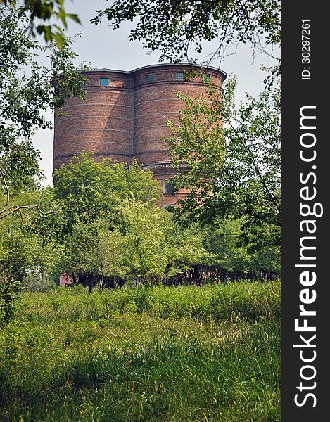 Brick water tower on a background of green trees and grass. Brick water tower on a background of green trees and grass.