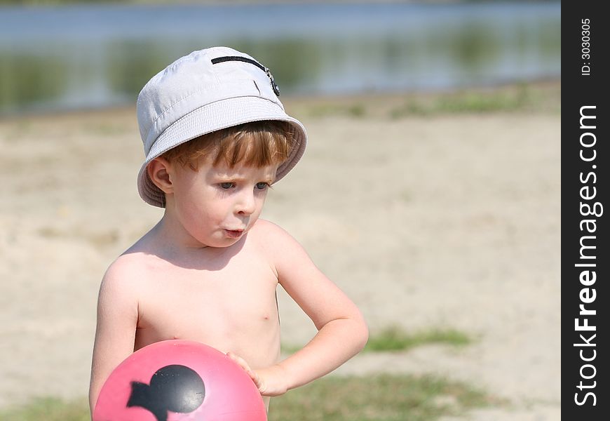 The boy on a beach holds a ball in hands. The boy on a beach holds a ball in hands