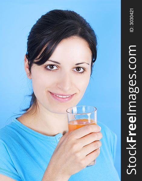 Young girl drinking juice on blue background