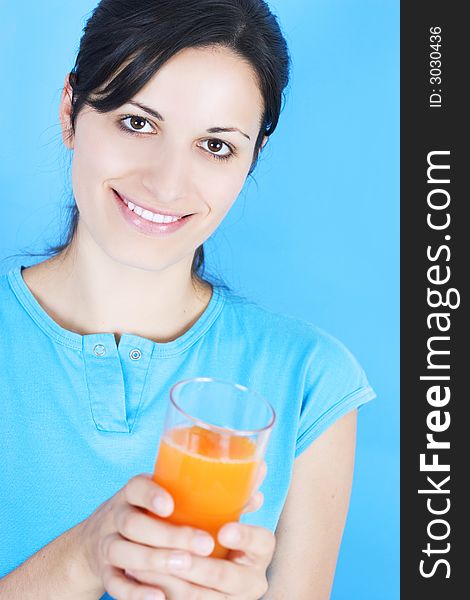 Young girl drinking juice on blue background