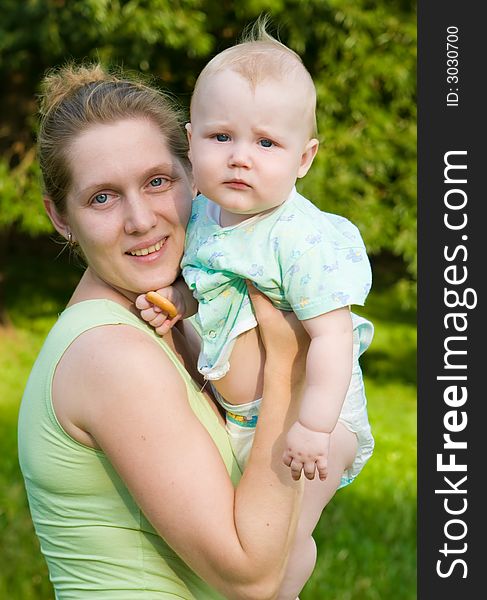 Portrait of mother with the child on hands on a background of green foliage. Portrait of mother with the child on hands on a background of green foliage