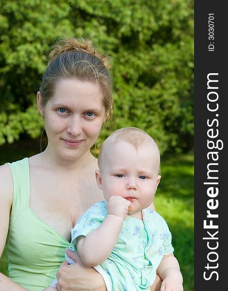 Portrait of mother with the child on hands on a background of green foliage. Portrait of mother with the child on hands on a background of green foliage