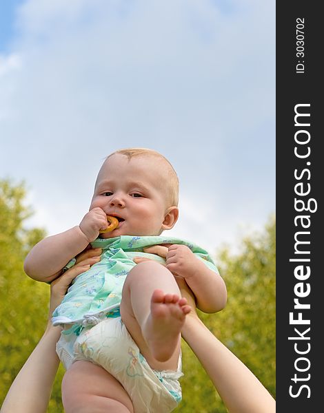 Small child on a background of green foliage and the blue sky with clouds. Small child on a background of green foliage and the blue sky with clouds