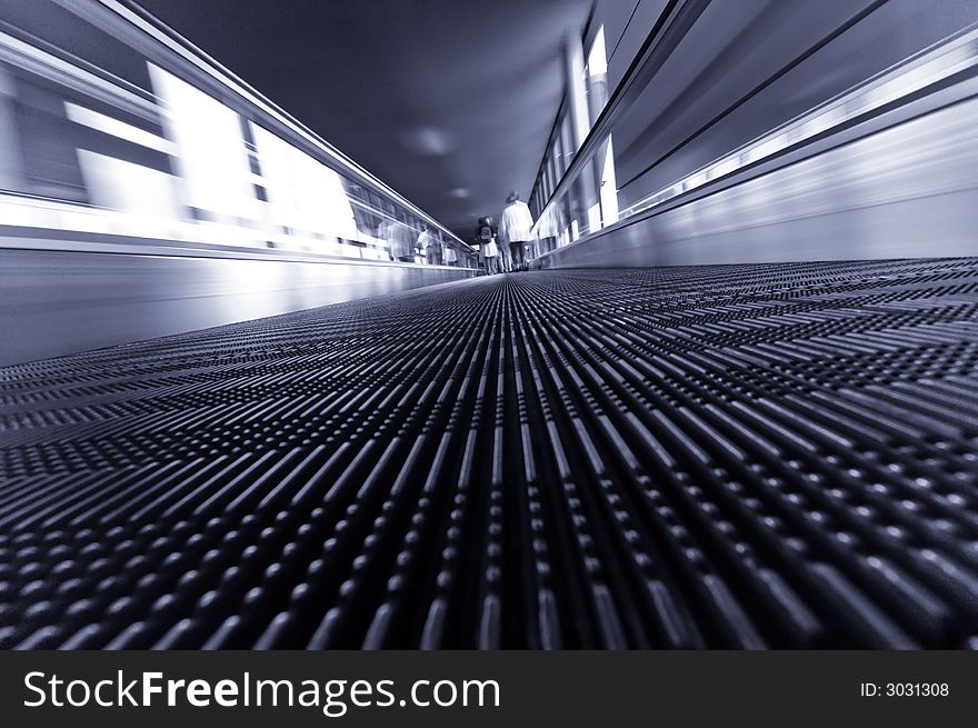 Abstract image of people traveling on a moving escalator at airport taken with an ultra wide angle lens