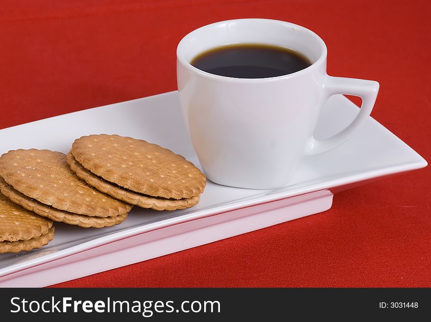 Cup  of  coffee and cream sandwich cookie  on the  plate. Cup  of  coffee and cream sandwich cookie  on the  plate