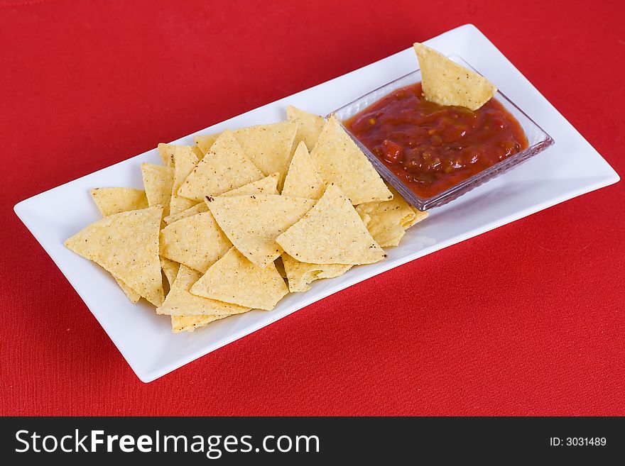 Nachos and salsa sauce on the red background