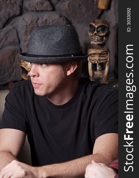 Young man wearing a gray hat with tribal artifacts in background