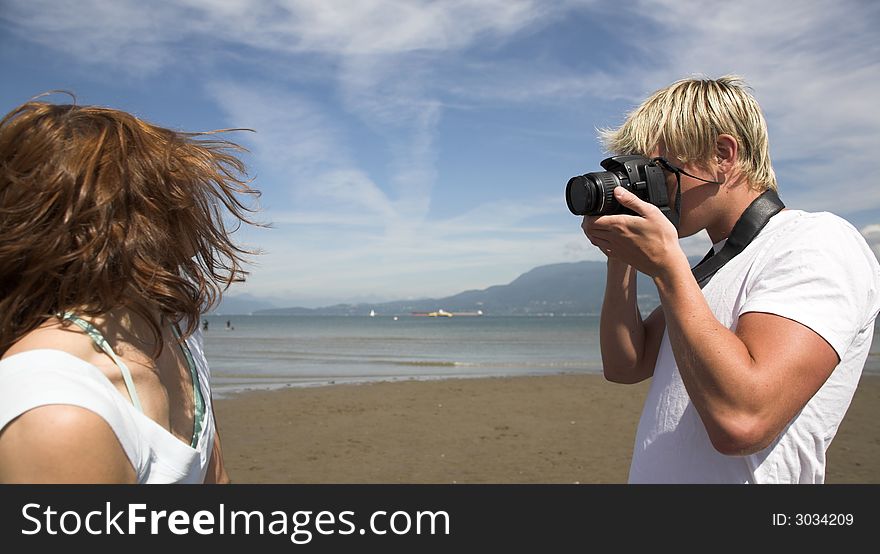 Young couple on the beach with dog in taking pictures