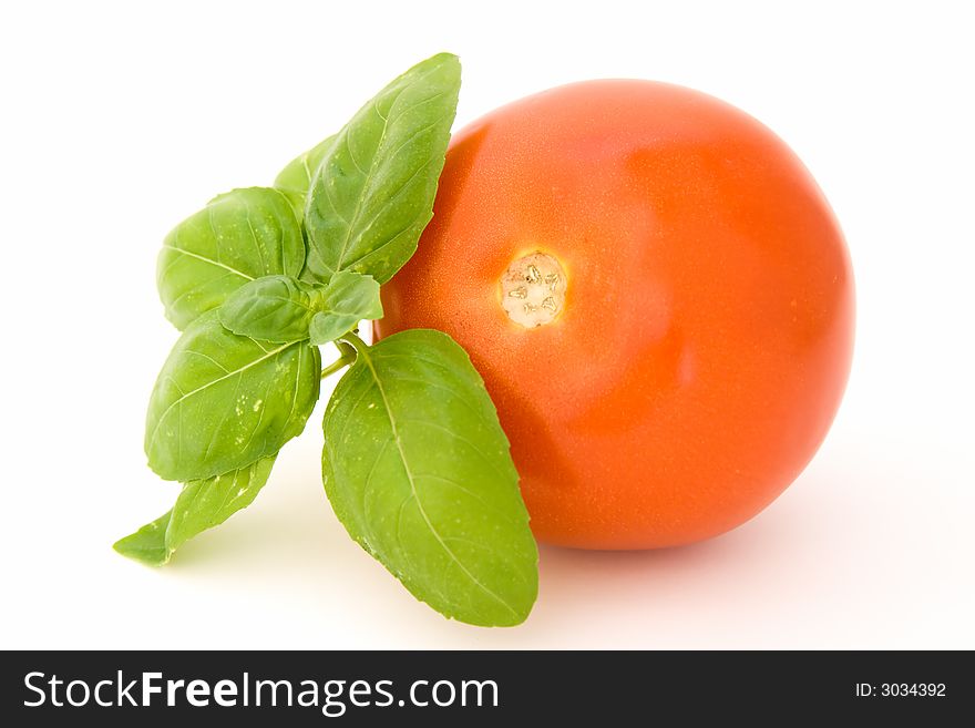 Tomato with basil isolated over white background