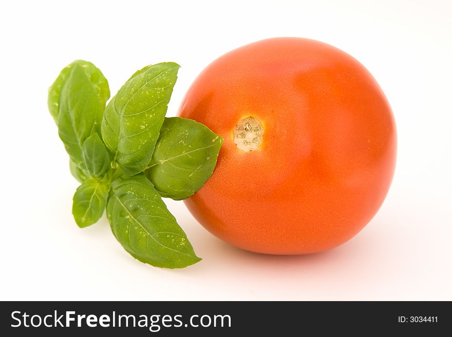 Tomato with basil isolated over white background