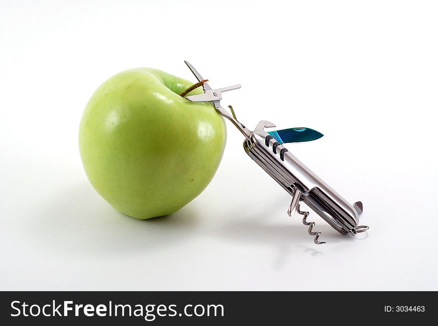 Swiss army knife aimed at an apple. Swiss army knife aimed at an apple