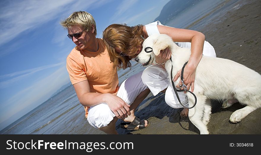 Young couple petting dog on the beach vancouver. Young couple petting dog on the beach vancouver