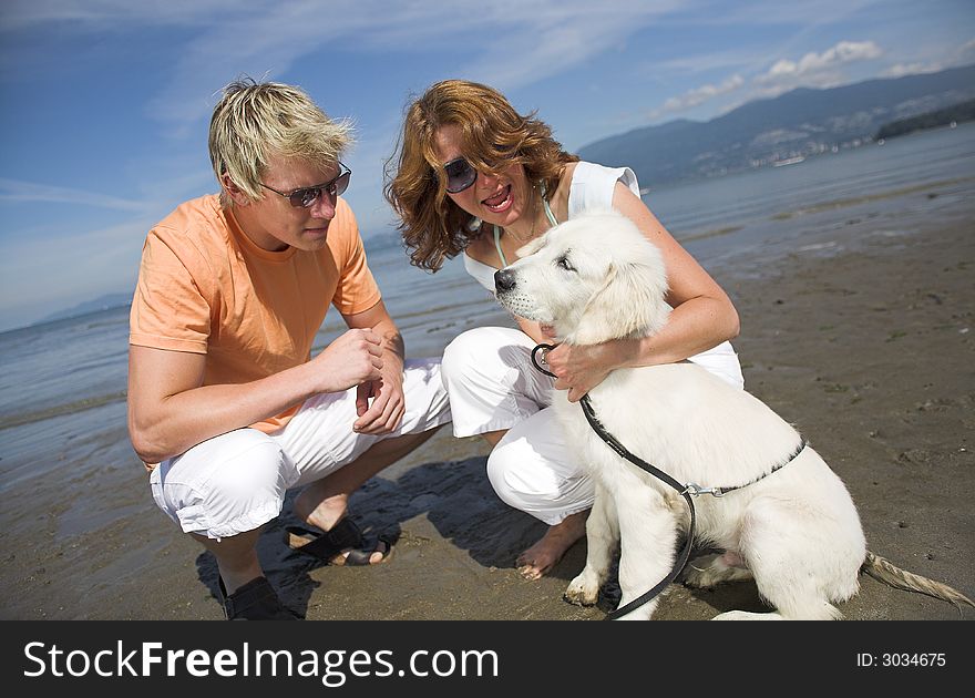 Young couple petting dog on the beach vancouver. Young couple petting dog on the beach vancouver