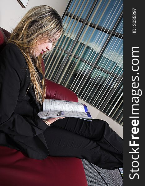 Woman reading a magazing on a red couch