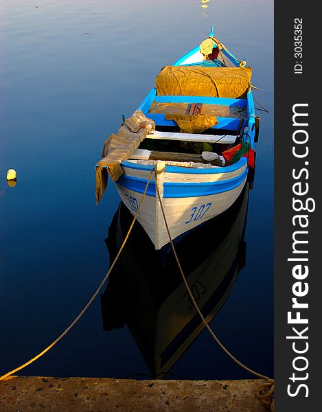 Small fishing boat at the dock surrounded by a calm sea.