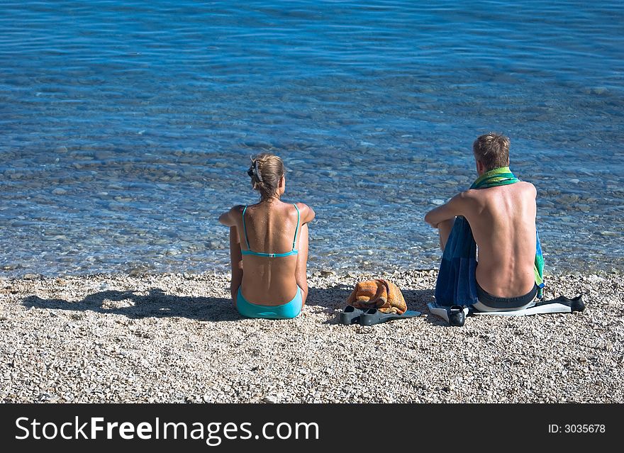 Young couple sit on the beach