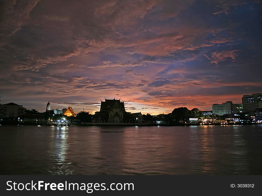A scenic view of the Chao Praya River in Bangkok, with a temple in the background. A storm shortly before sunset produces a colourful and dramatic sky. A scenic view of the Chao Praya River in Bangkok, with a temple in the background. A storm shortly before sunset produces a colourful and dramatic sky