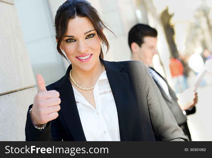 Portrait of an attractive businesswoman showing thumb up sign. Couple working.