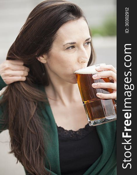 Beautiful young woman with brown hair and eyes holding a mug of beer. Beautiful young woman with brown hair and eyes holding a mug of beer.