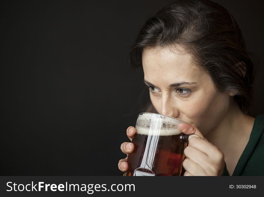 Beautiful young woman with brown hair and eyes holding a mug of beer. Beautiful young woman with brown hair and eyes holding a mug of beer.