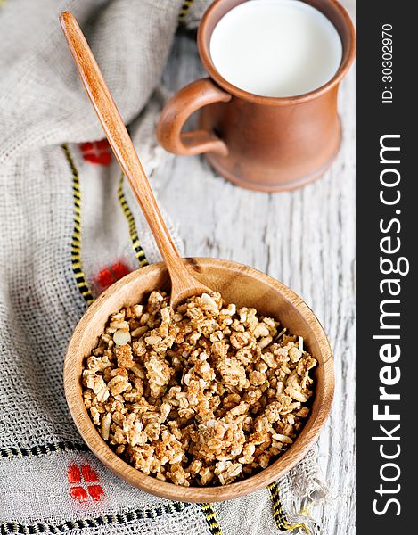 Muesli in wooden plate and milk in clay mug