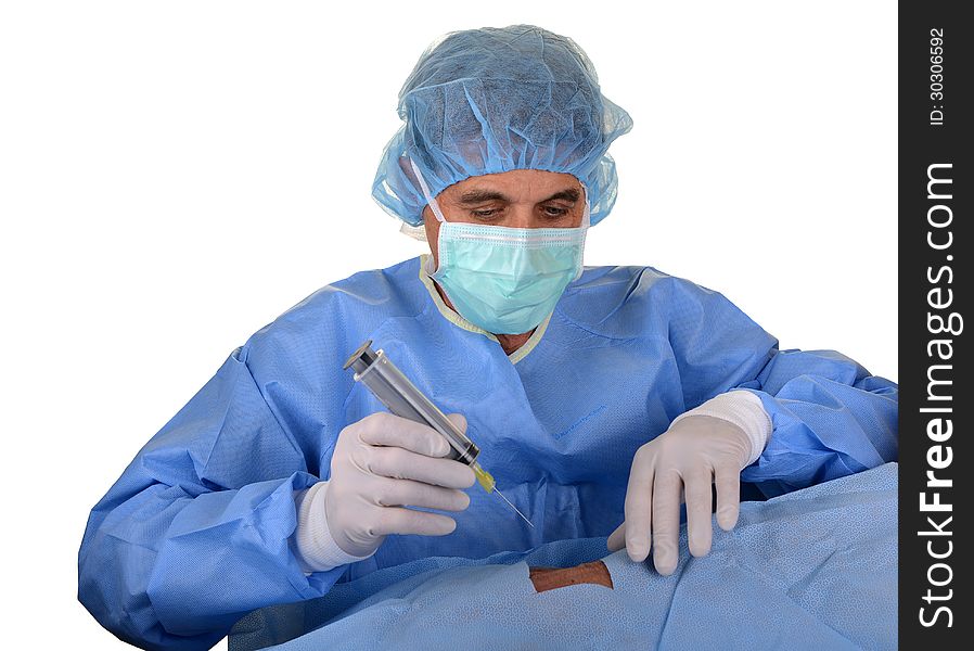 Doctor wearing blue sterile gown with hair cover, mask and gloves with large needle and syringe. Doctor wearing blue sterile gown with hair cover, mask and gloves with large needle and syringe