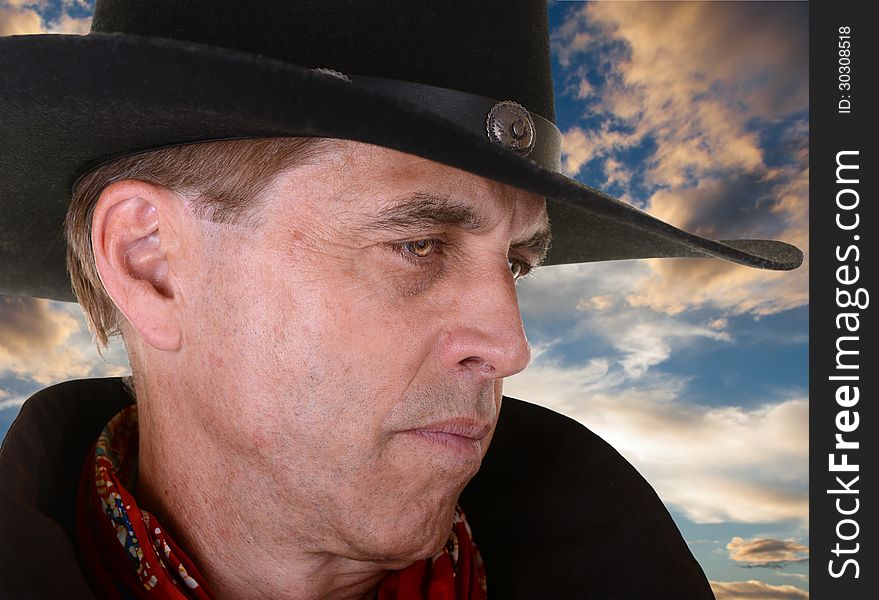 Profile of handsome serious man wearing a black cowboy hat and red bandana against beautiful sunset. Profile of handsome serious man wearing a black cowboy hat and red bandana against beautiful sunset