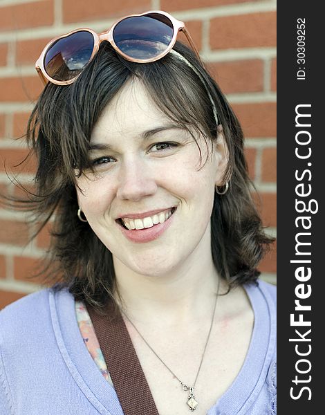 Color photo of young woman smiling, wearing sunglasses