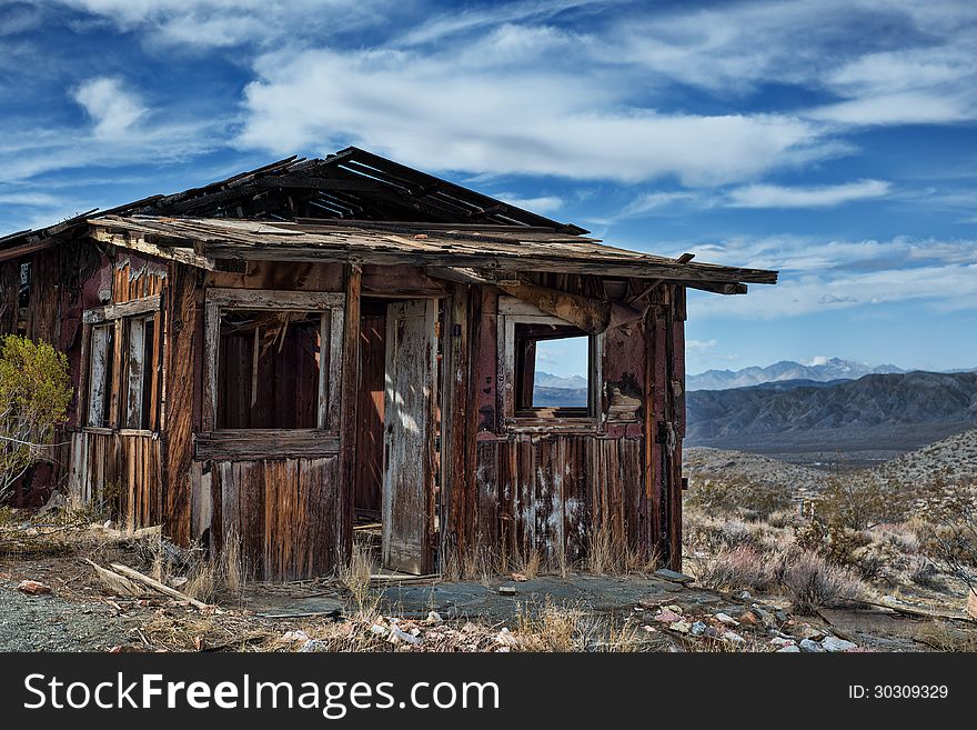 Decayed cabin on hill in Randsberg California with beautiful cloudy sky and mountains in the back ground. Decayed cabin on hill in Randsberg California with beautiful cloudy sky and mountains in the back ground