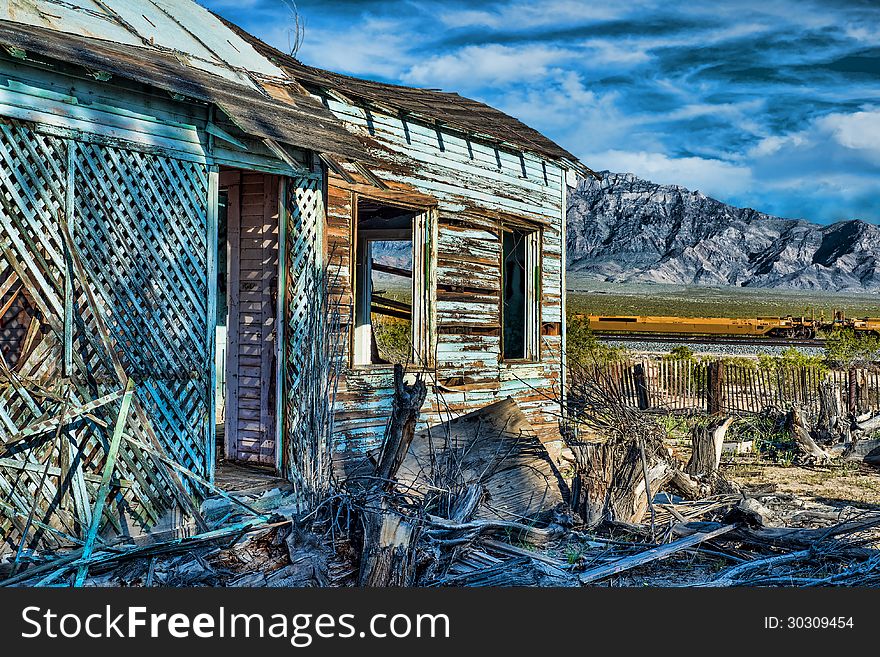 Abanonded tourquoise house in Mojave National Preserve with old picket fence train tracks and dramatic mountains in the background. Abanonded tourquoise house in Mojave National Preserve with old picket fence train tracks and dramatic mountains in the background