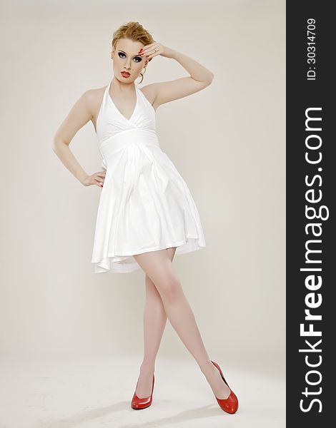 Portrait of a beautiful adult sensuality blonde woman in white dress red lips and shoes on light background. Portrait of a beautiful adult sensuality blonde woman in white dress red lips and shoes on light background